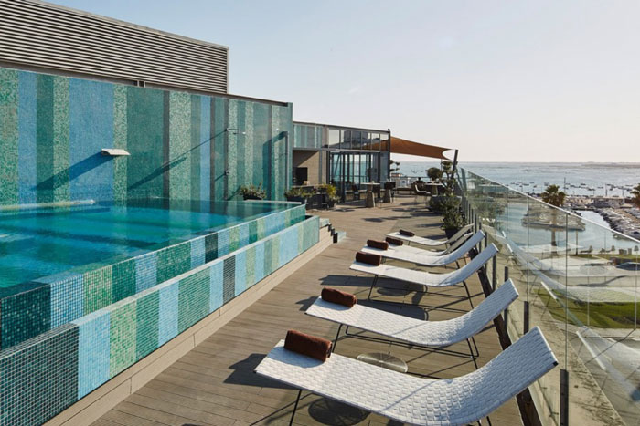 Rooftop pool with ocean view and lounge chairs.