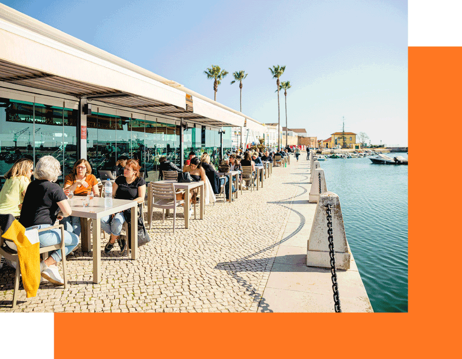 People dining at outdoor waterfront restaurant.