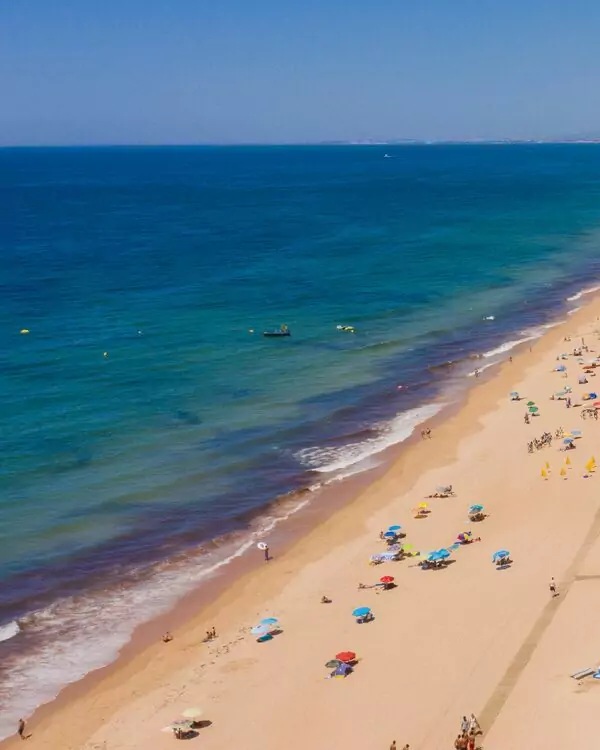 Sandy beach with umbrellas and people relaxing.
