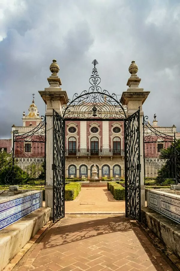 Ornate gate opens to historical mansion gardens.
