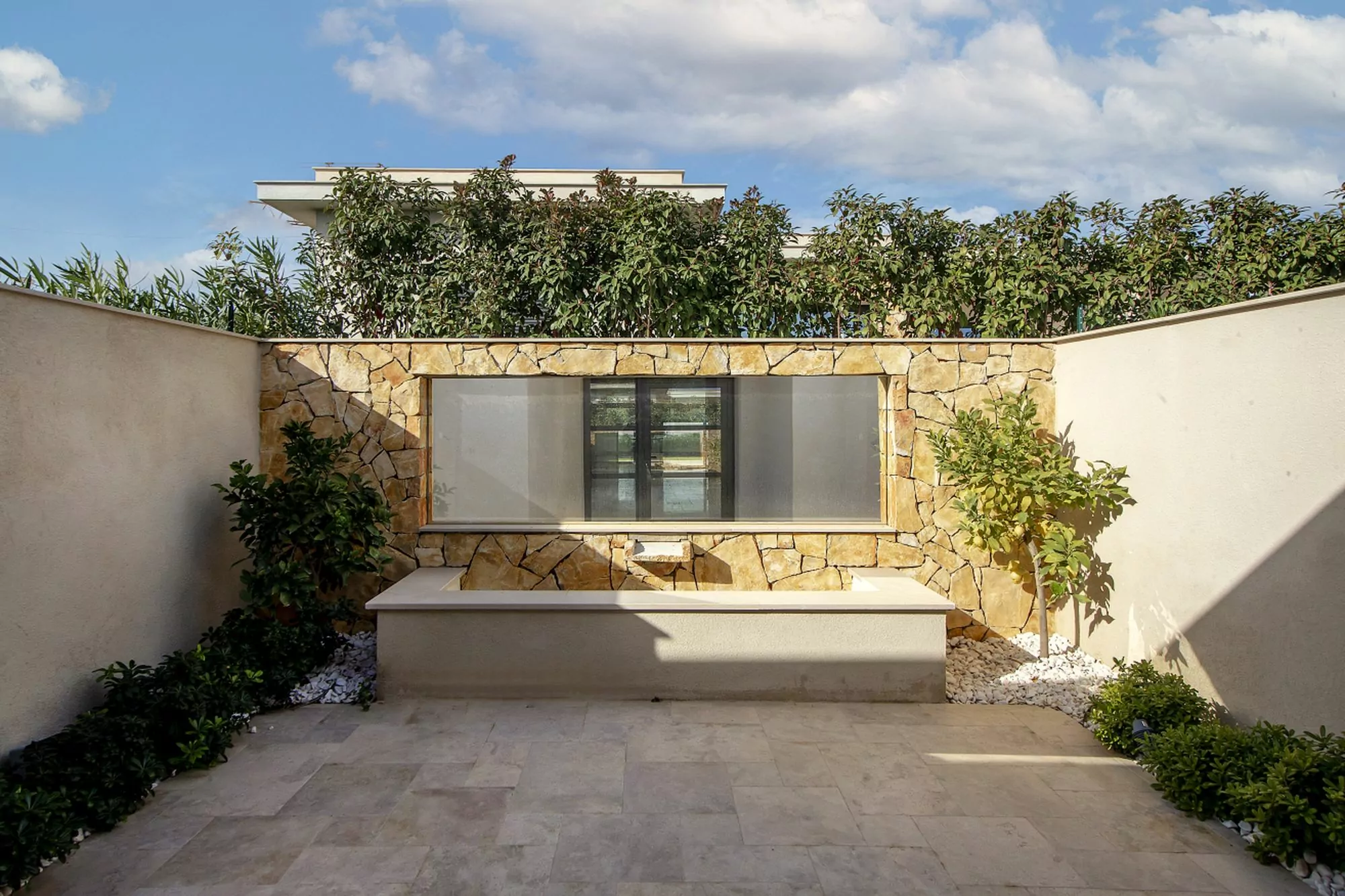 Patio d’une villa de luxe à Quinta de Faro avec mur en pierre naturelle et banc